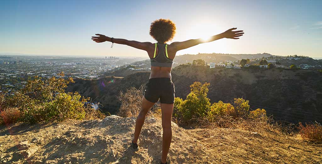 woman standing on mountaintop, arms outstretched