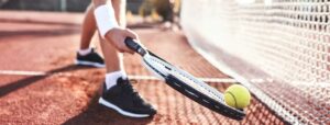 tennis player picking up ball with racket